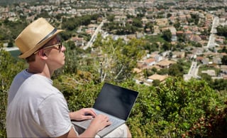 Freelancer guy working on the street, sitting on a mountain, enjoying the beautiful scenery