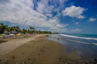 Beautiful view of the beach with sand, and builsings behind in a beautiful day in with sunny weather in a blue sky in Same, Ecuador