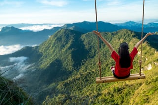 tourists sit and swing on the top of the high hill