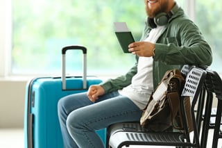 handsome man with passport sitting on chair in hall of airport