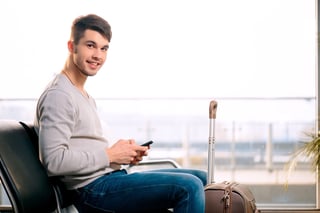 handsome smiling man in casual wear holding his luggage