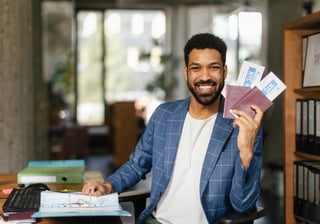 young happy man holding plane tickets in office