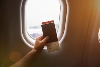 Hand Holding Passport With Airplane Ticket On Plane Window