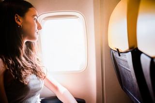 Young Girl Looking Through The Window While Traveling On Airplane