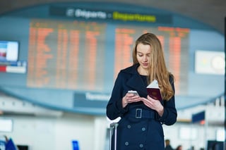 Young Woman In International Airport Near The Flight Information Board Holding